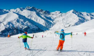 Cute skier boy with his mother having fun in a winter ski resort.