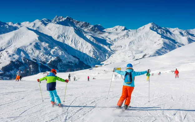 Cute skier boy with his mother having fun in a winter ski resort.