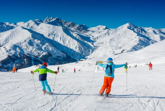Cute skier boy with his mother having fun in a winter ski resort.
