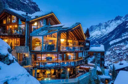 large glass and wooden chalet under snow at night