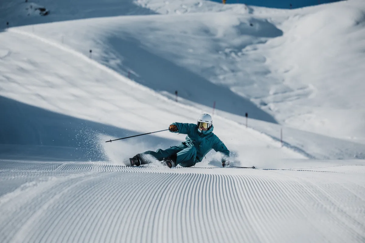 Skier making a deep carving turn on a groomed slope