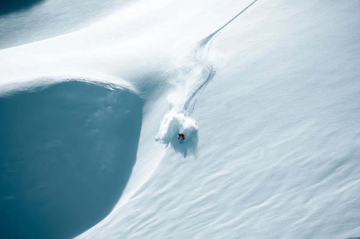 Skier in red carving fresh powder on a steep slope in Saalbach Hinterglemm