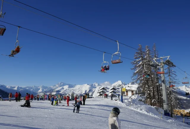 Skiers enjoying the sunlit pistes of Pila ski resort with panoramic views of the Aosta Valley mountains,
