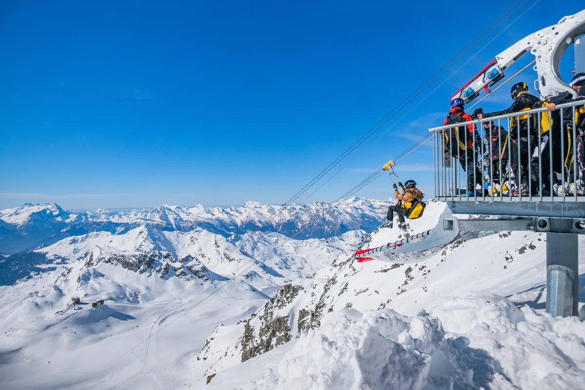A person riding the zipline over snowy mountains at Mont-Fort
