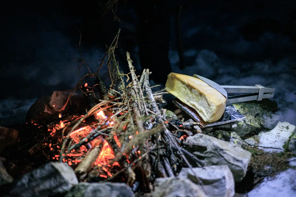 Raclette sits on an open fire to heat and melt