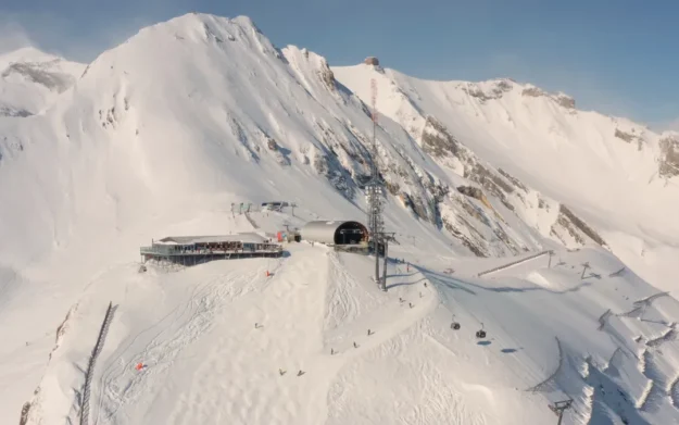 Aerial view of snowy mountain summit and ski lift infrastructure above Anzère