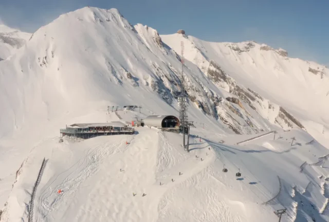 Aerial view of snowy mountain summit and ski lift infrastructure above Anzère