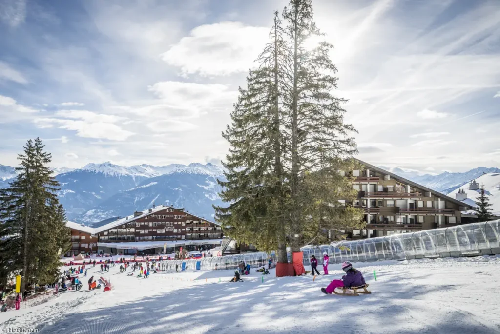 View of Anzère ski village with families enjoying the beginner slopes and mountain panorama