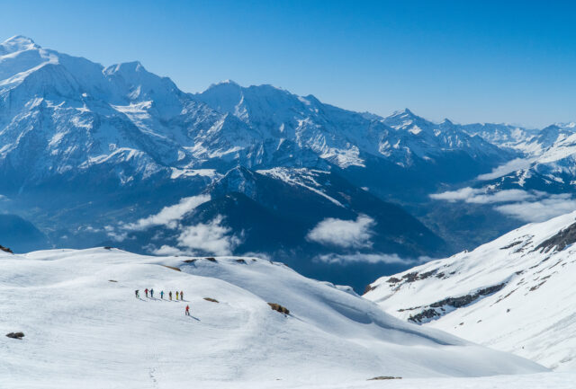 Line of ski tourers crossing snowfields below Mont Blanc
