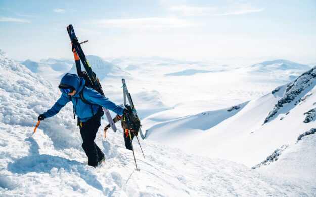 Skiers walking over mountain.