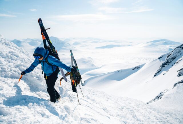 Skiers walking over mountain.