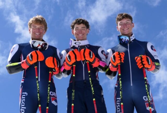 Zak, Luca and Freddy Carrick-Smith in GB race suits holding their ski poles