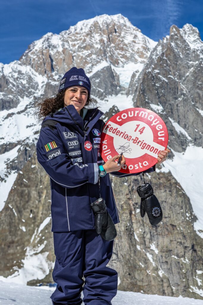 Federica Brignone holding the Courmayeur piste 14 sign named after her, with Mont Blanc behind