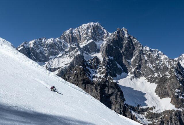Skier descending a steep snowy slope beneath the Mont Blanc massif in Courmayeur
